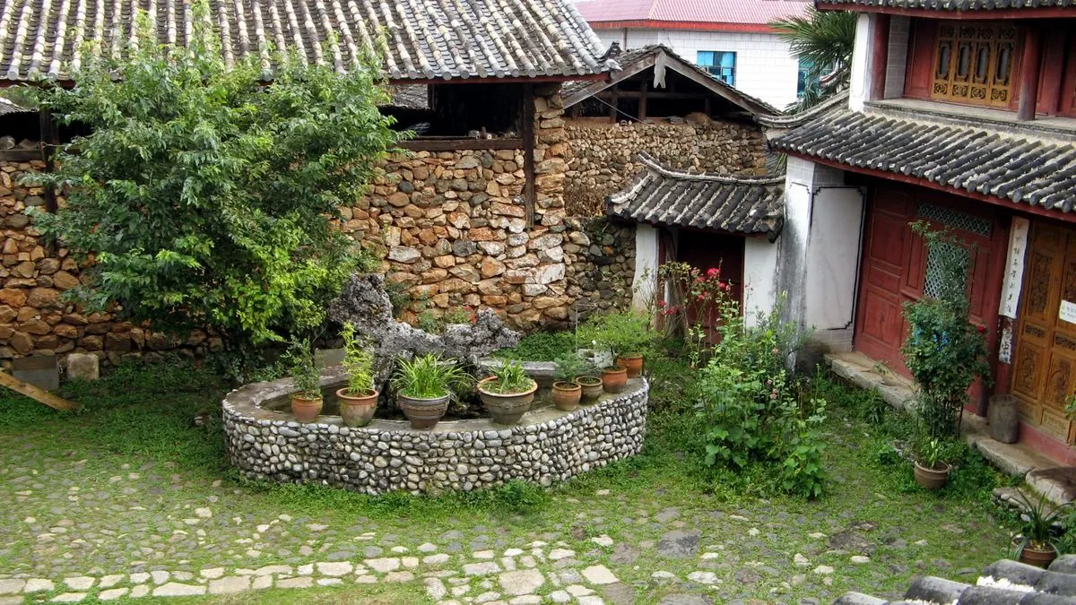 丽江玉湖村纳西族院落，石墙与瓦房掩映在绿树间